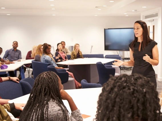 Female teacher addressing university students in a classroom