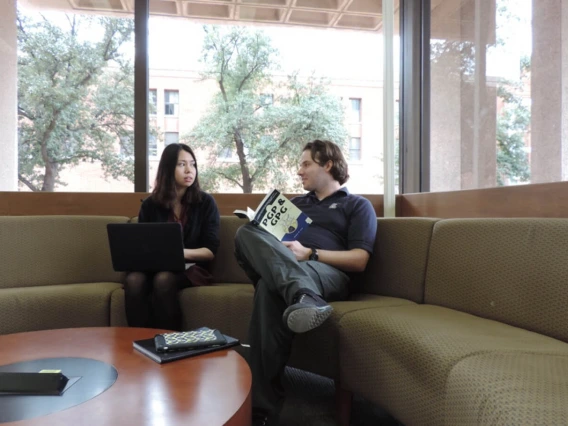 Two people sitting at the library working on an assignment