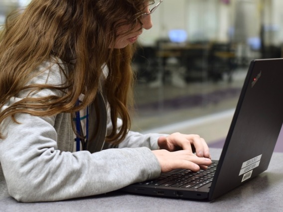 Student typing on a Lenovo Thinkpad laptop.