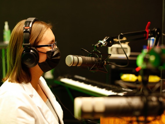 Person records a podcast using a microphone in the Media Recording Studio.