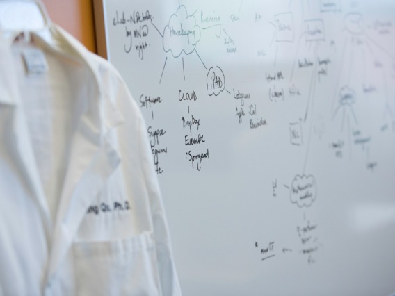 A person wearing white coat standing in front of a whiteboard