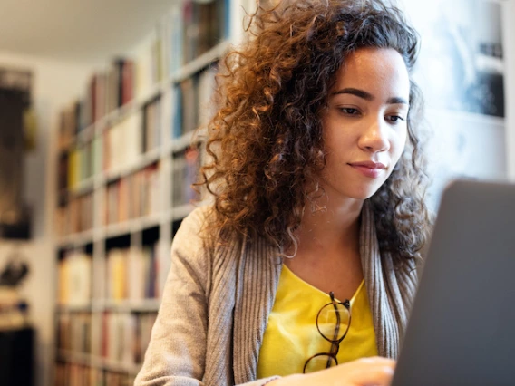 woman typing on laptop in library