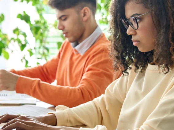 A male and a female student typing on laptops