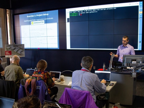 A librarian leading a workshop in a room with a large screen