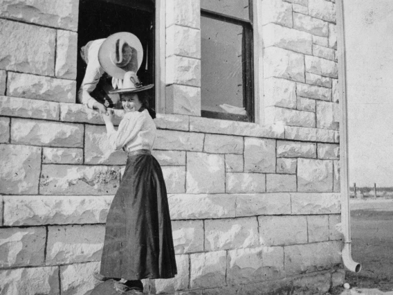 Two students holding hands through a window