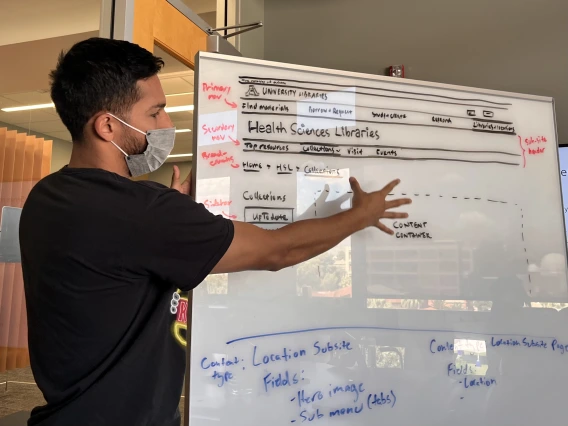 Man pointing at web page sketches on a whiteboard