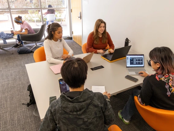 students sitting at a table working on laptops