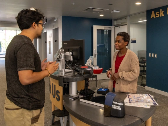 staff member helping visitor at library ask us desk