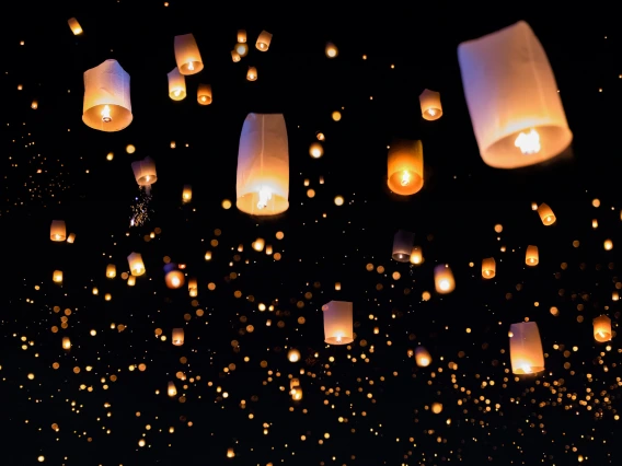 Hundreds of paper lanterns floating up into the dark night sky