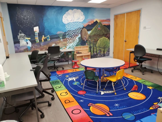 room with wall mural, tables, chairs, and a multi-color rug