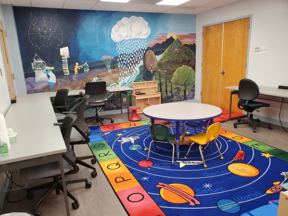 room with wall mural, tables, chairs, and a multi-color rug