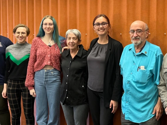 seven people standing against orange backdrop