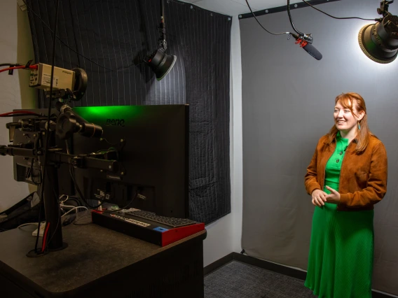 A library staff member records a video presentation in the One Button Studio in front of the green screen.