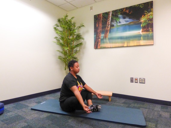 Student sitting on floor meditating in the Reflection room