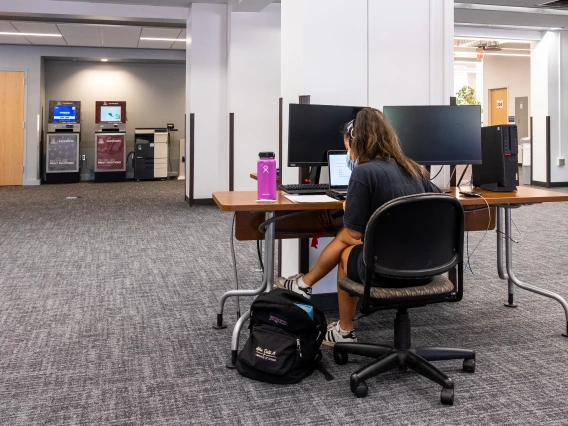 student on her laptop with double monitors