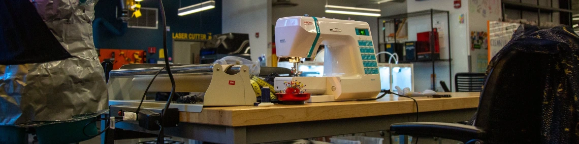 Sewing machine on a table surrounded by fabrics and clothes