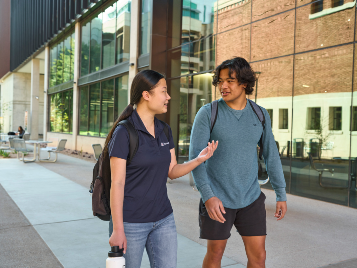 Two students chatting while walking to class