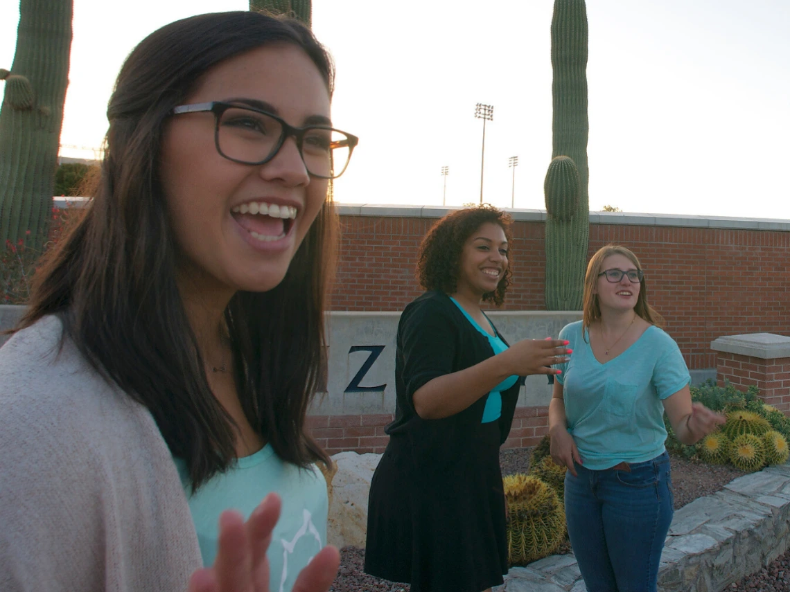 Three students wave at incoming students