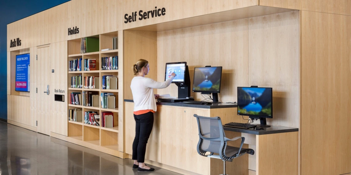 Student checking out a book using the self-checkout counter