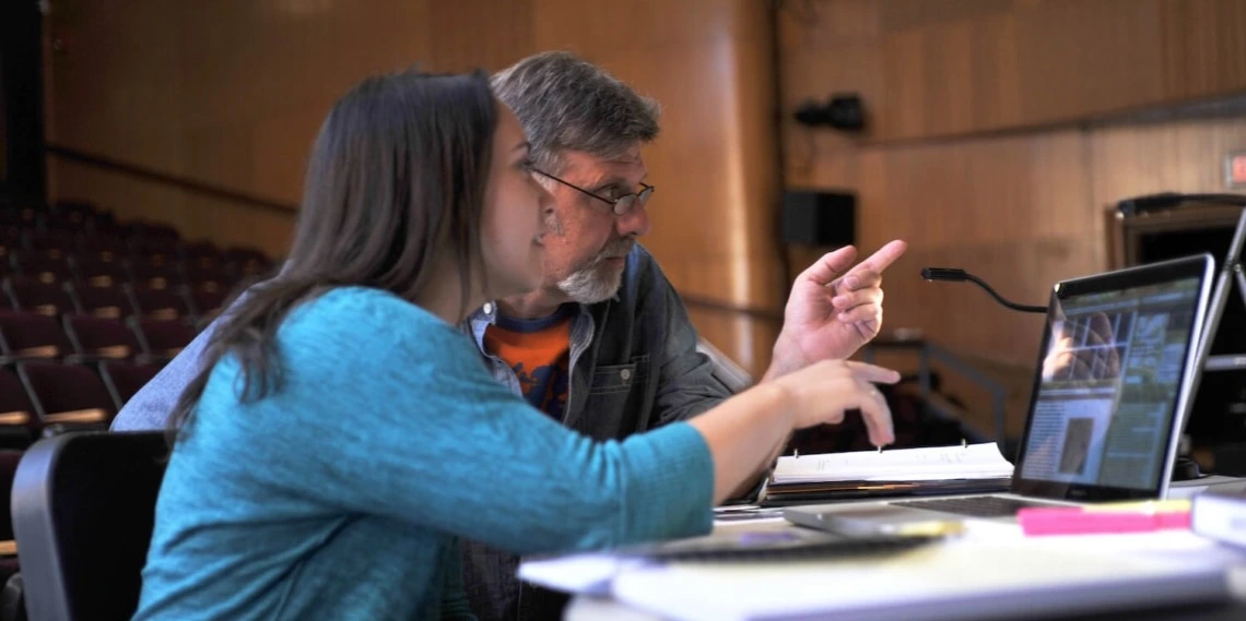 A man and a woman reviewing materials on a laptop
