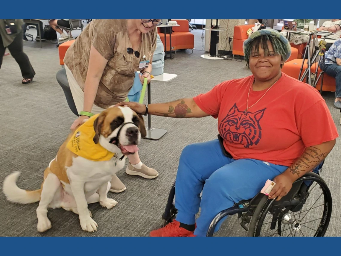 A student poses with a therapy dog at Pause for Paws