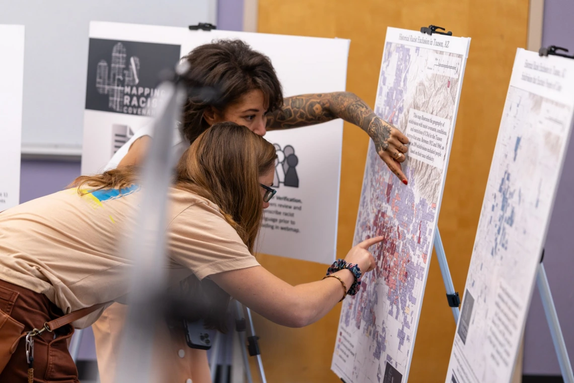 two people looking closely and pointing at a map