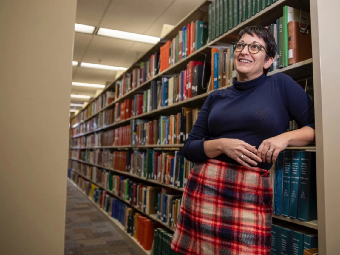 Megan Senseney casually poses by a large stack of books