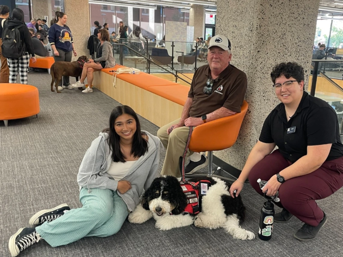 Student and staff pose with a therapy dog at Pause for Paws