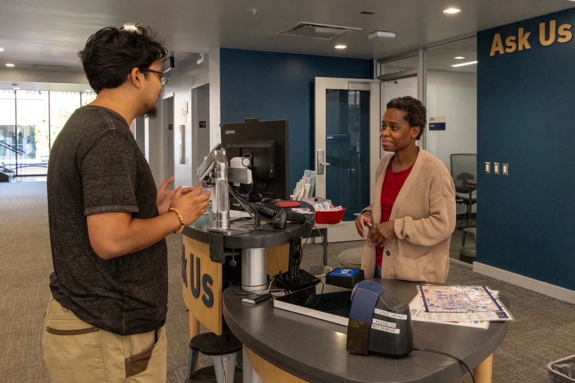 staff member helping visitor at library ask us desk