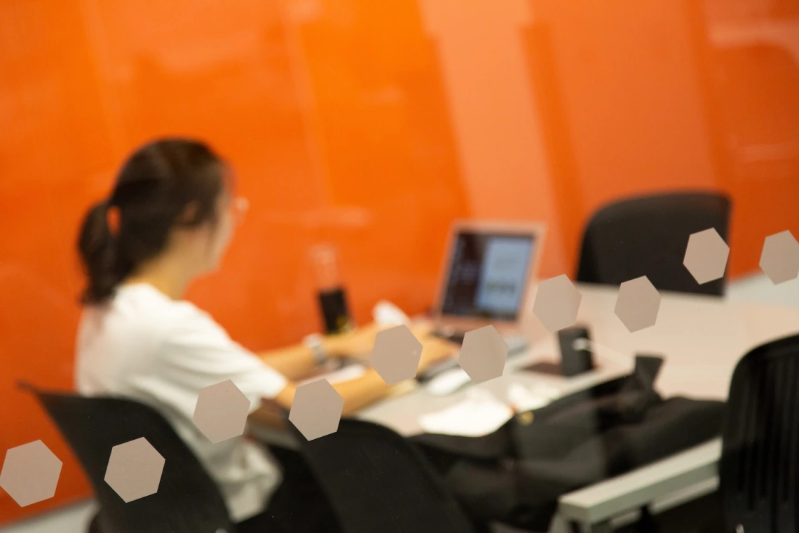 student in white shirt with a laptop sitting in study room 