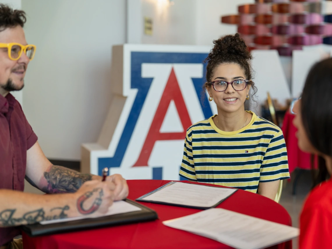 three students sitting at table talking