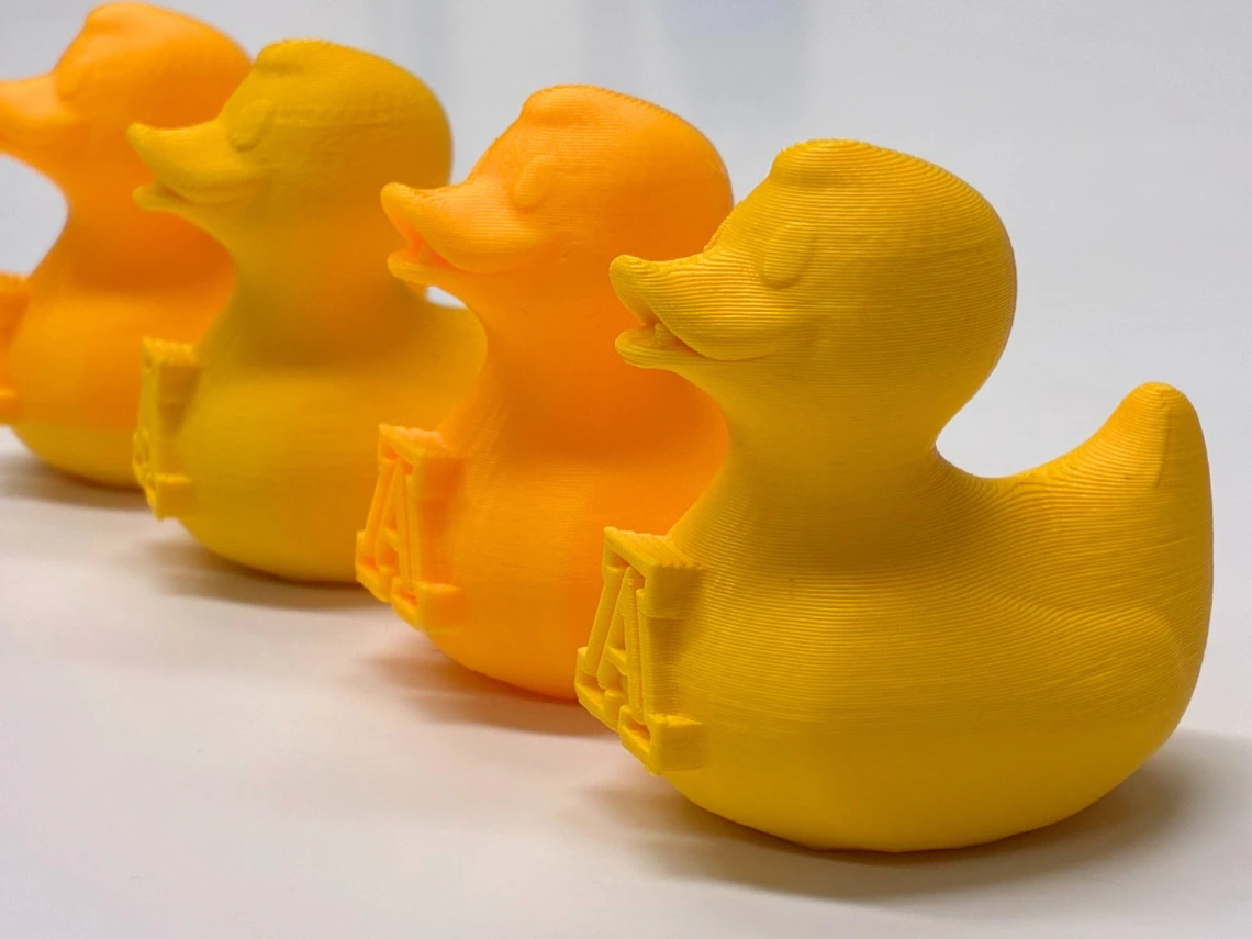 A row of 3D printed ducks on a white tabletop