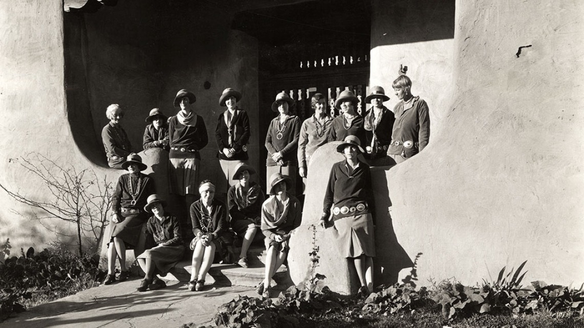 A group of women, couriers with the group Indian Detour, stand in the exterior entry of an adobe building.