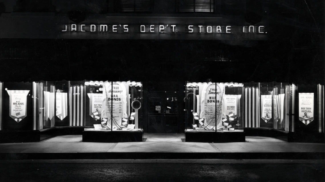 Black and white photograph of the Jacome's Department Store storefront. Windows display advertisements for war bonds.