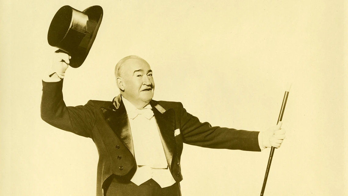 Joseph E. Howard in suit with tails holding top hat and cane.