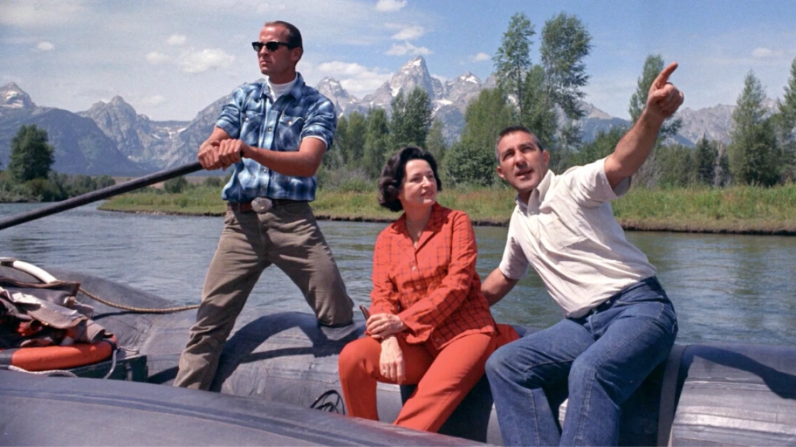 Three people sitting in a boat in a lake