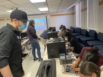 employees watch students build workstations