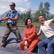 Three people sitting in a boat in a lake