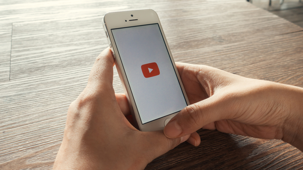Holding a smartphone with YouTube logo on screen