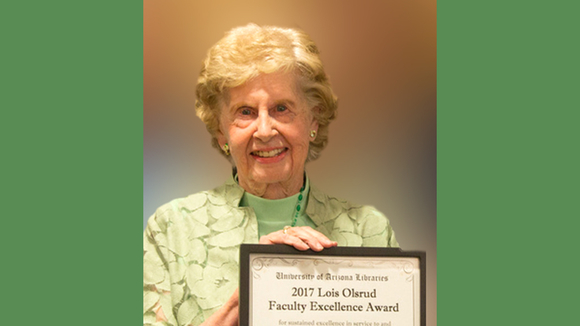 Lois Olsrud holding a framed certificate award