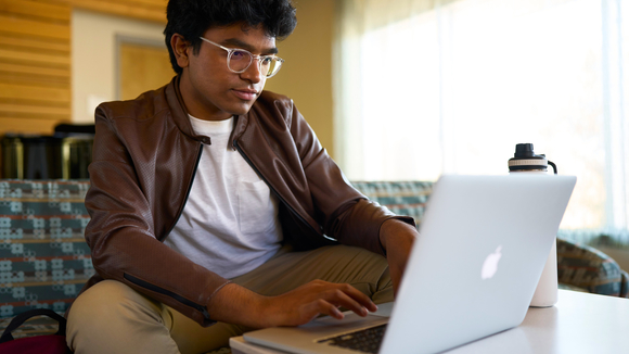 student sitting on couch looking at laptop
