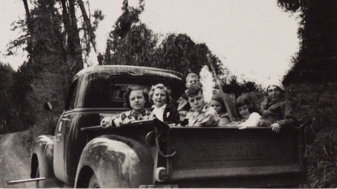 Several children from the Apache County 4-H club sit in the back of a pickup truck in 1951