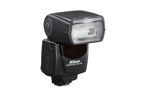 The flash control device has a flash head on top of a black base with "Nikon" branding written in white letters on the device. The device is hand-held.